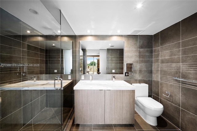 bathroom featuring tile walls, a bathtub, vanity, toilet, and tile patterned floors