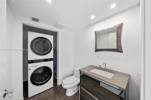 bathroom featuring vanity, tile patterned floors, toilet, and stacked washer / dryer