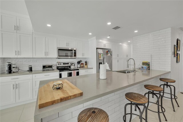 kitchen featuring a breakfast bar, sink, white cabinetry, kitchen peninsula, and stainless steel appliances