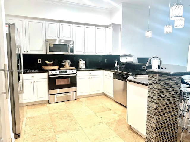 kitchen with hanging light fixtures, appliances with stainless steel finishes, white cabinets, and kitchen peninsula