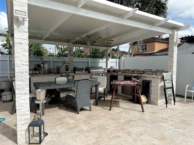 view of patio featuring area for grilling, exterior bar, ceiling fan, and an outdoor kitchen