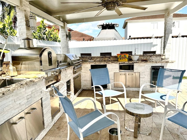 view of patio / terrace featuring ceiling fan, an outdoor kitchen, area for grilling, and wine cooler