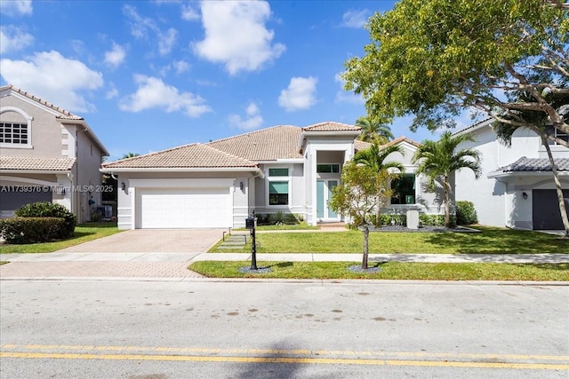 mediterranean / spanish house with a garage and a front lawn