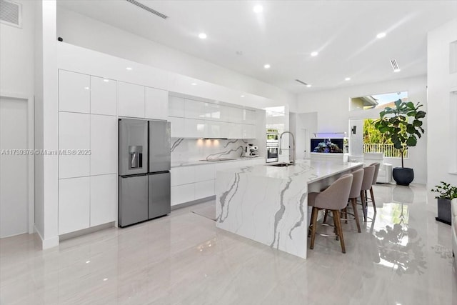 kitchen featuring white cabinetry, a large island, a kitchen breakfast bar, and stainless steel fridge with ice dispenser