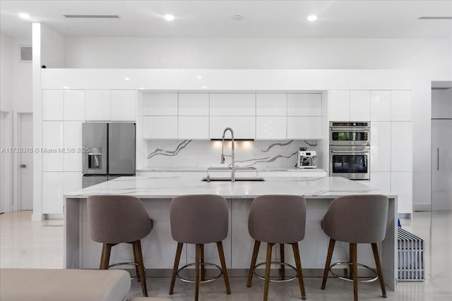 kitchen featuring white cabinetry, an island with sink, sink, a kitchen breakfast bar, and stainless steel appliances