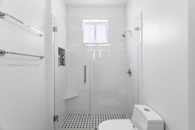 bathroom featuring a shower with shower door and toilet