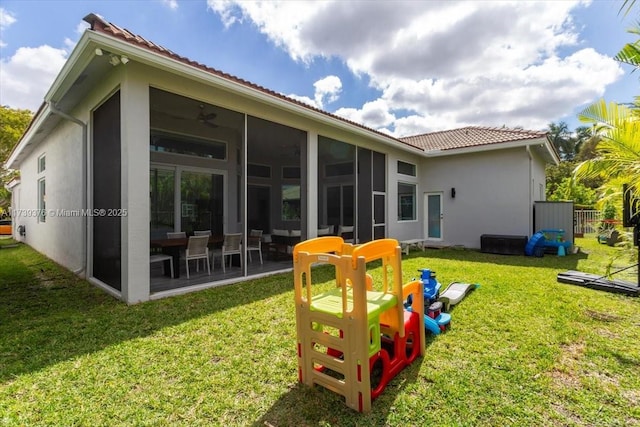 rear view of house featuring a yard and a sunroom