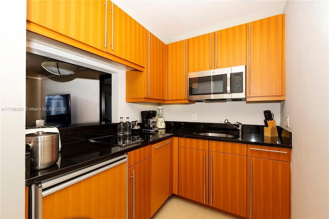 kitchen featuring sink, dark stone countertops, and light tile patterned floors