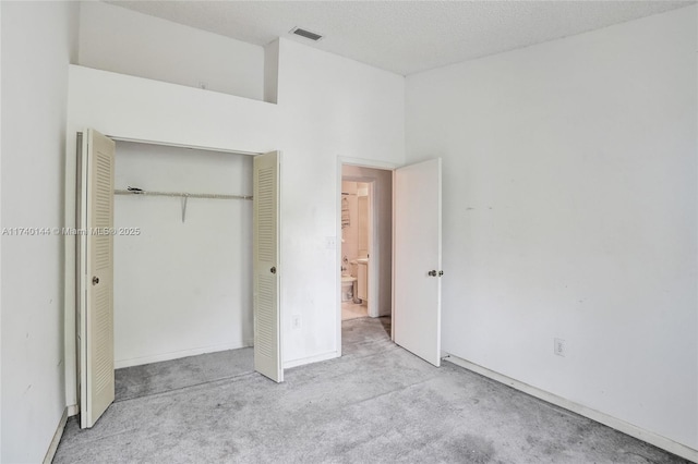 unfurnished bedroom featuring light carpet, a closet, and a textured ceiling