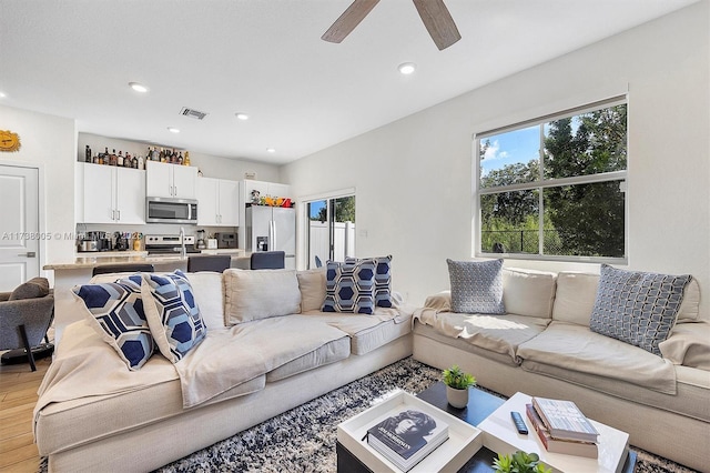 living room with light hardwood / wood-style flooring and ceiling fan