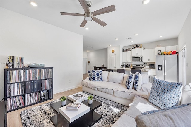 living room with light hardwood / wood-style floors and ceiling fan