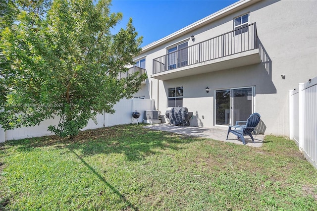 rear view of property featuring a balcony, central AC, a patio area, and a lawn