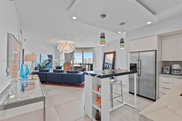 kitchen with light tile patterned floors, light stone countertops, white cabinets, stainless steel fridge with ice dispenser, and decorative light fixtures