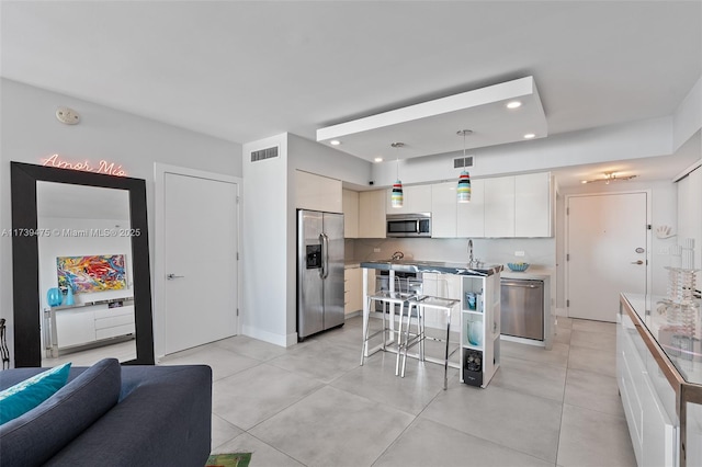 kitchen with decorative light fixtures, a breakfast bar area, stainless steel appliances, visible vents, and modern cabinets