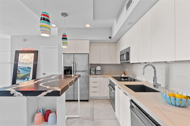 kitchen with decorative light fixtures, appliances with stainless steel finishes, white cabinets, a sink, and modern cabinets