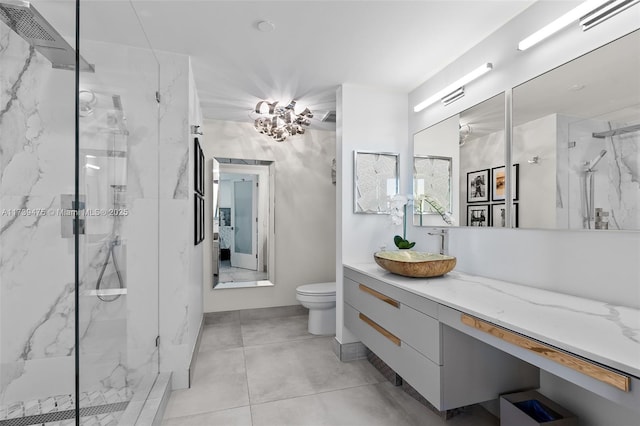 bathroom with toilet, a marble finish shower, vanity, and tile patterned floors