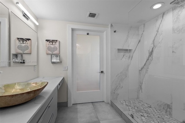 bathroom with a marble finish shower, visible vents, and vanity