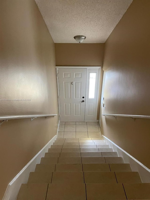 doorway to outside featuring light tile patterned flooring and a textured ceiling