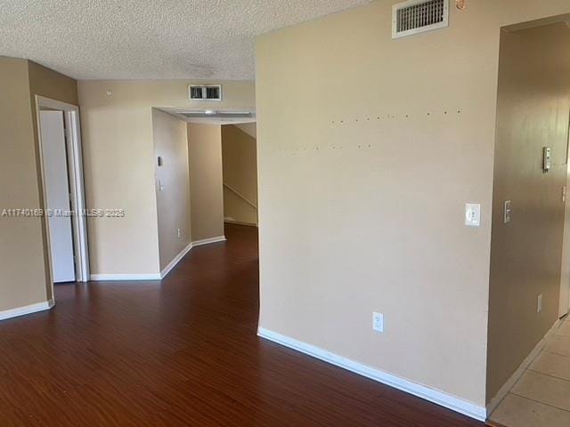 empty room with hardwood / wood-style floors and a textured ceiling