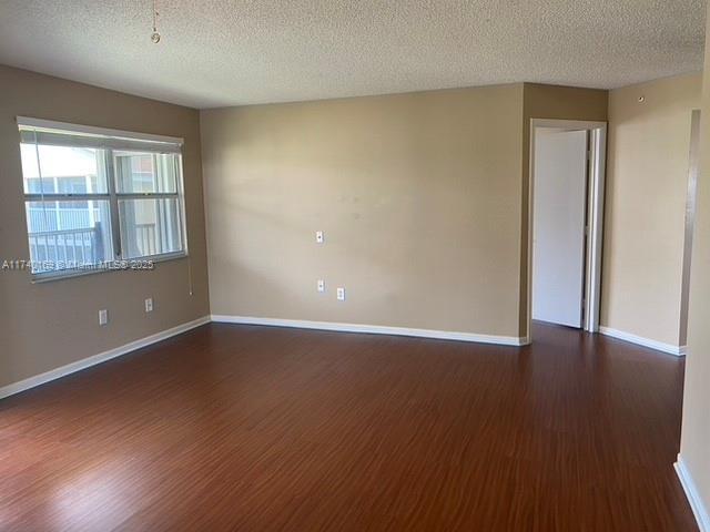 unfurnished room featuring dark wood-type flooring and a textured ceiling