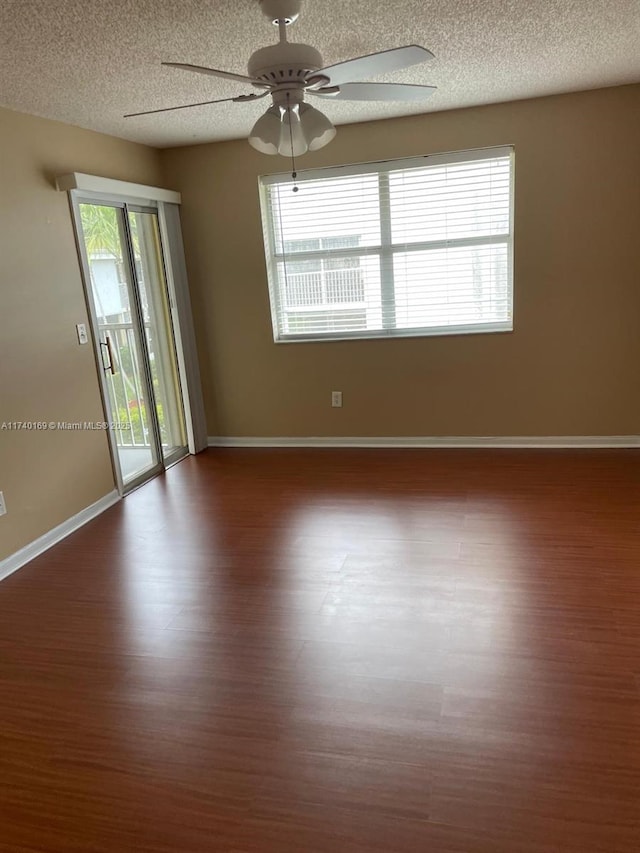 empty room featuring plenty of natural light, wood-type flooring, and a textured ceiling