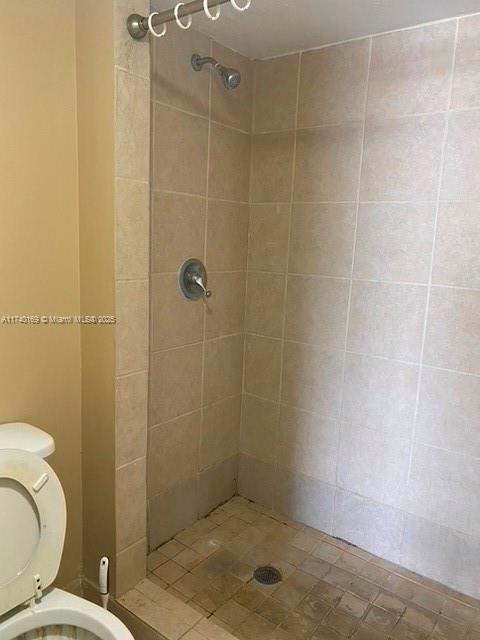 bathroom featuring tiled shower and toilet