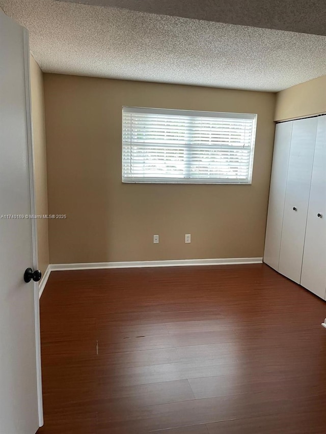 unfurnished bedroom featuring hardwood / wood-style flooring, a closet, and a textured ceiling