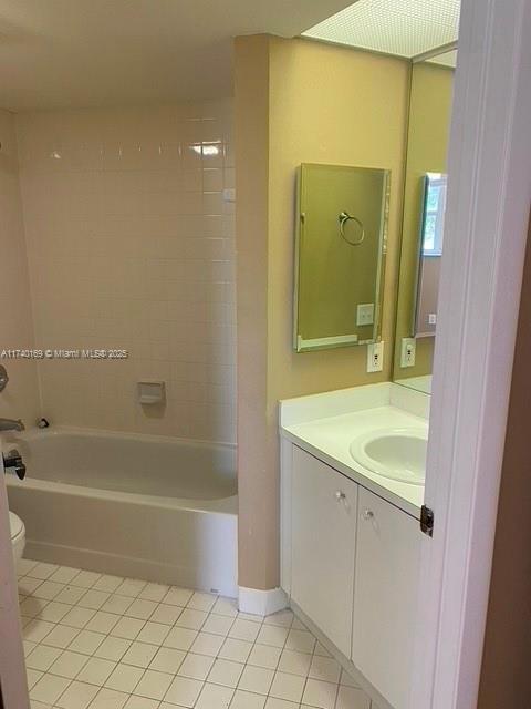 full bathroom with tiled shower / bath, vanity, tile patterned floors, and toilet