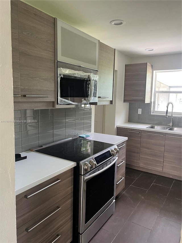 kitchen with appliances with stainless steel finishes, sink, dark tile patterned flooring, and decorative backsplash