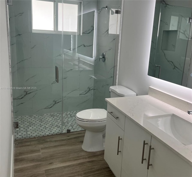 bathroom featuring vanity, hardwood / wood-style flooring, toilet, and walk in shower