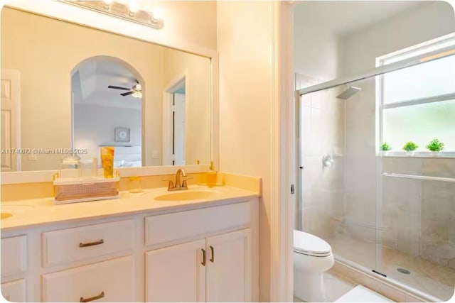 bathroom with vanity, ceiling fan, a shower with door, and toilet