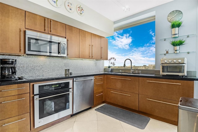 kitchen featuring appliances with stainless steel finishes, sink, light tile patterned floors, and decorative backsplash