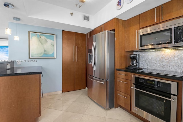 kitchen featuring tasteful backsplash, dark stone countertops, light tile patterned floors, pendant lighting, and stainless steel appliances