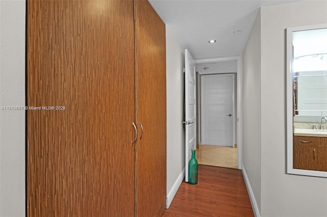 corridor featuring wood-type flooring and sink