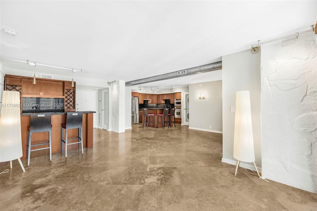 kitchen with track lighting, appliances with stainless steel finishes, a kitchen breakfast bar, and kitchen peninsula