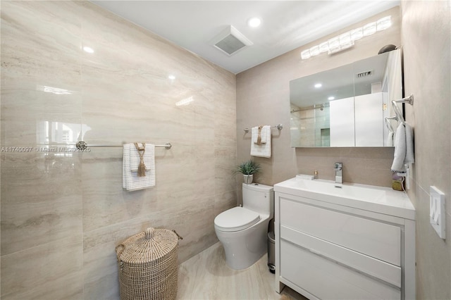 bathroom with vanity, toilet, an enclosed shower, and tile walls