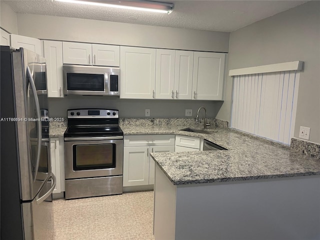 kitchen with white cabinetry, sink, light stone counters, kitchen peninsula, and stainless steel appliances