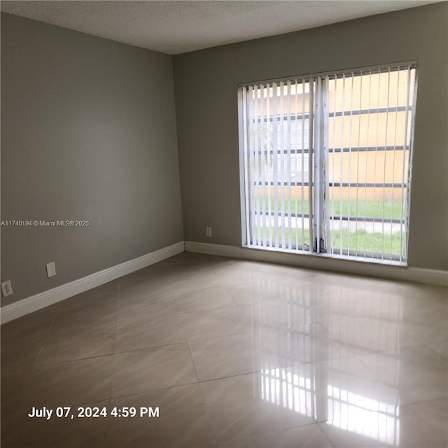 tiled spare room with a textured ceiling