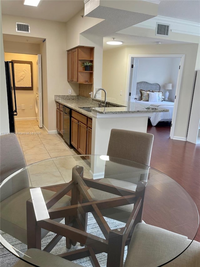 kitchen with light tile patterned flooring, sink, kitchen peninsula, dishwasher, and light stone countertops