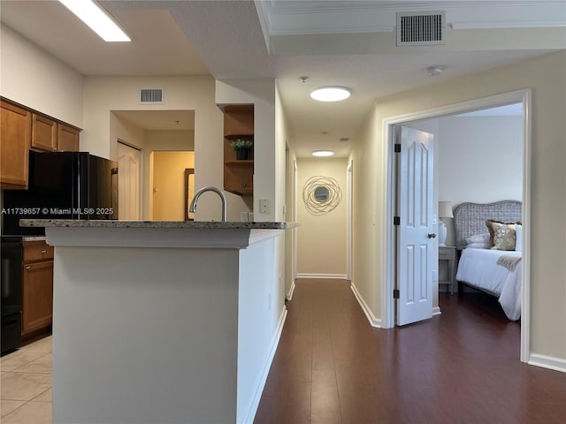 kitchen with stone countertops, sink, light wood-type flooring, and kitchen peninsula