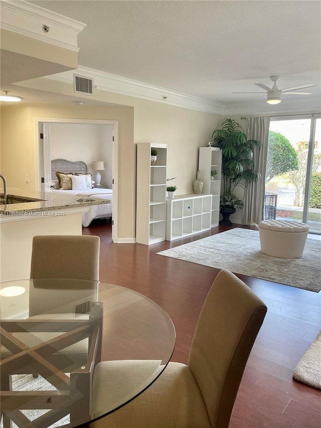 dining room with wood-type flooring, sink, a textured ceiling, and crown molding