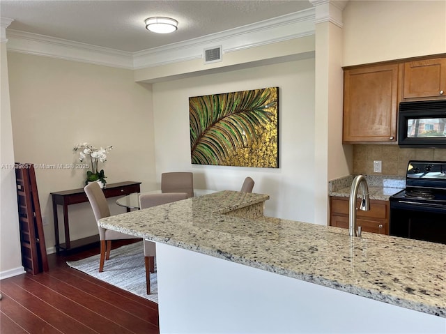 kitchen featuring dark hardwood / wood-style floors, backsplash, ornamental molding, light stone counters, and black appliances