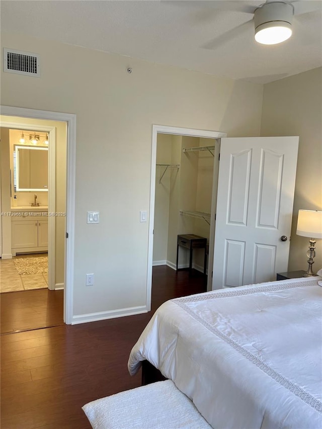 bedroom featuring a walk in closet, dark wood-type flooring, ceiling fan, and a closet