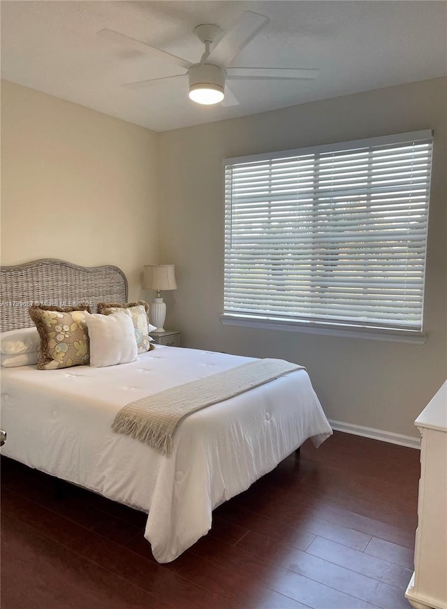 bedroom featuring ceiling fan, dark hardwood / wood-style flooring, and multiple windows