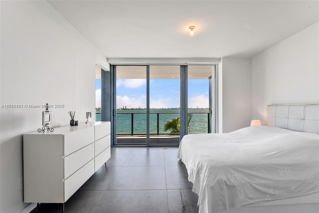 bedroom featuring expansive windows, a water view, and access to exterior