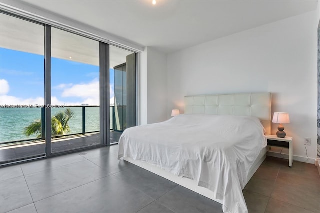 bedroom with access to exterior, dark tile patterned flooring, expansive windows, and a water view