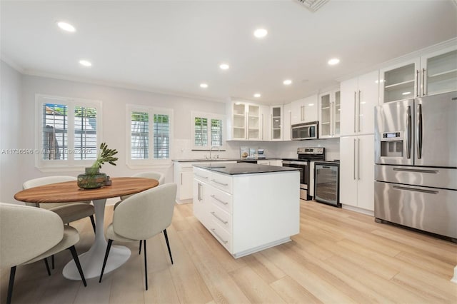 kitchen with white cabinetry, stainless steel appliances, a kitchen island, beverage cooler, and light wood-type flooring