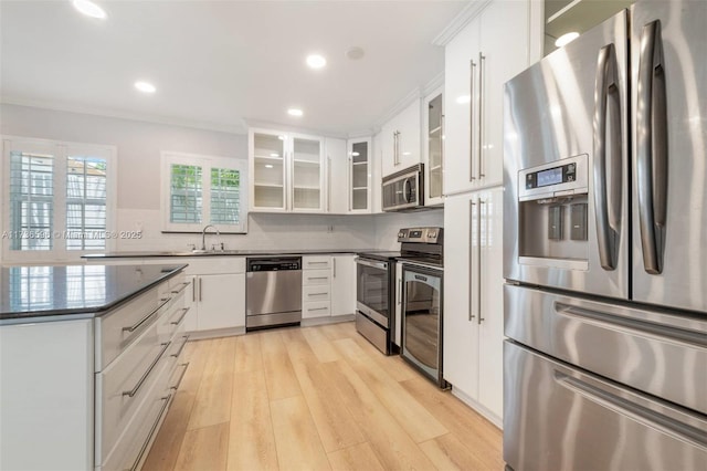 kitchen featuring appliances with stainless steel finishes, backsplash, white cabinets, and light wood-type flooring