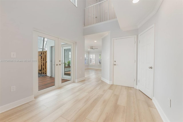 interior space with a high ceiling, light hardwood / wood-style floors, and french doors