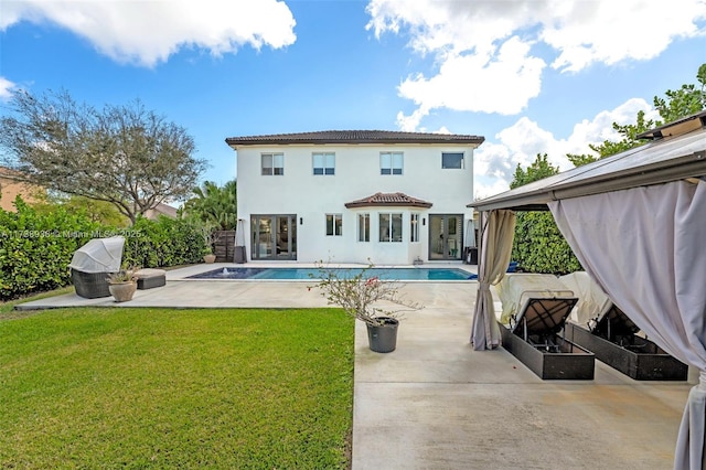 rear view of property with a yard, a patio, an outdoor pool, and stucco siding